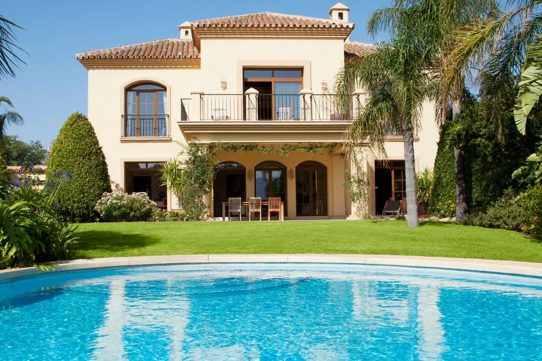 A villa with its pool, lawn and palm trees