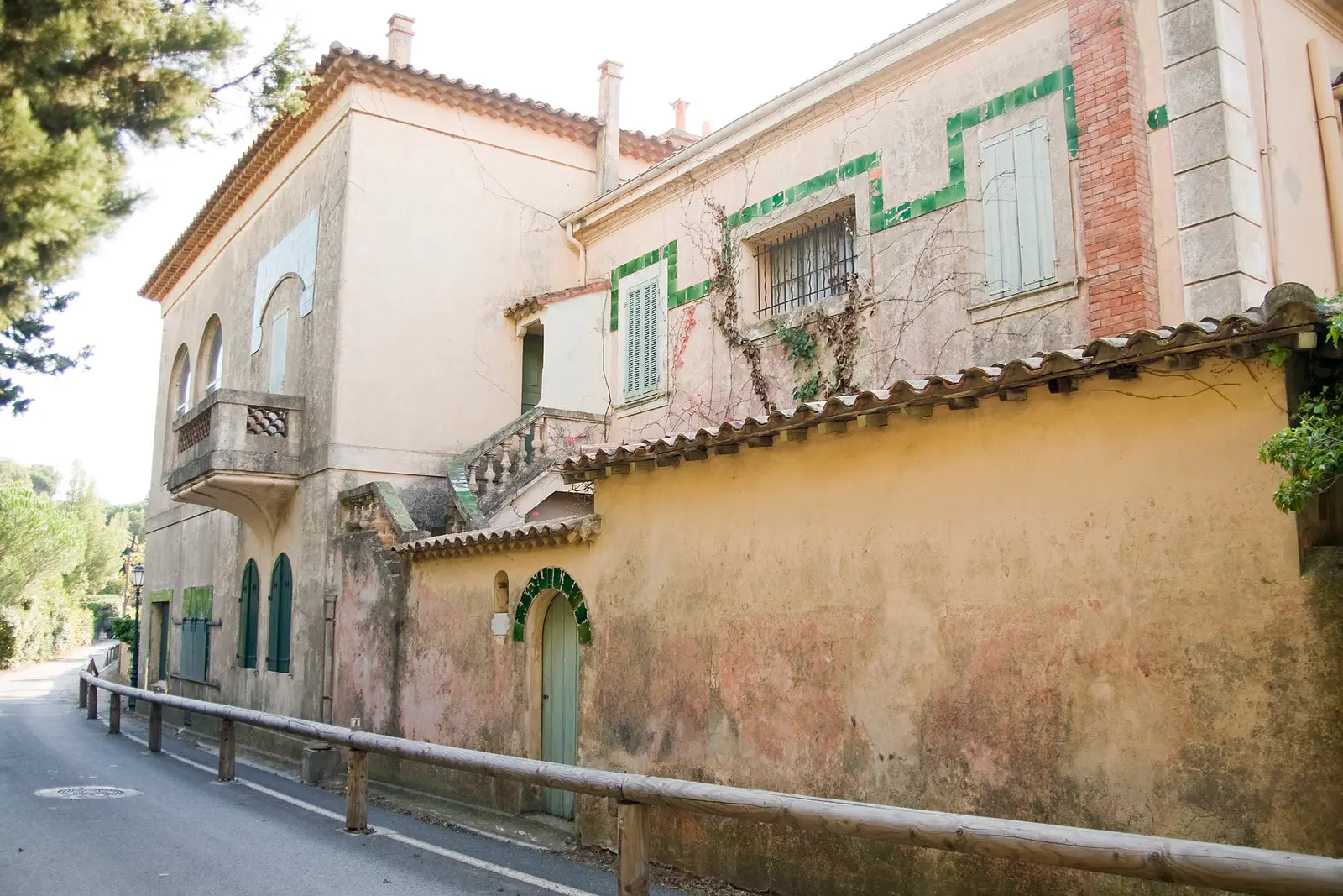 Stone villa in Saint-Tropez under cypresses, wooden gate and gravel path