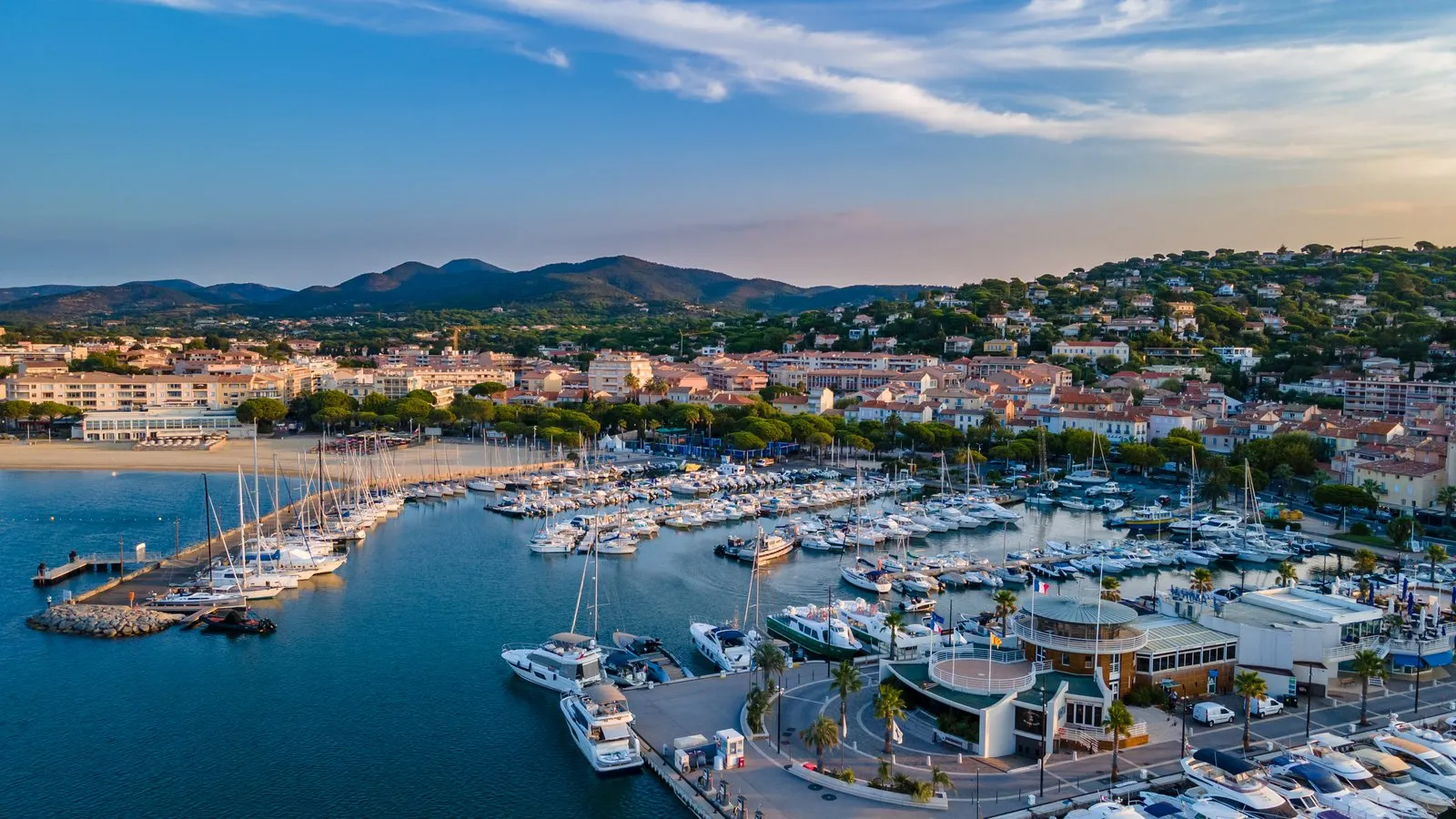 O porto de Sainte-Maxime ao pôr do sol visto do céu, a cidade e as colinas atrás