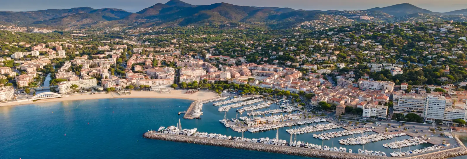 Sainte-Maxime from the air: the marina, the beach and the town at the foot of the Maures hills