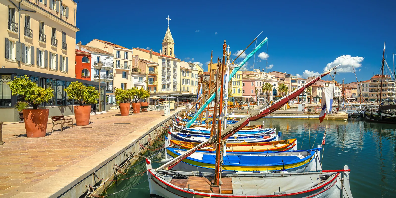 Os barcos tradicionais atracados no cais e as fachadas coloridas do porto de Sanary-sur-Mer