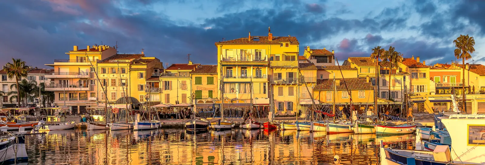 The port of Sanary-sur-Mer at sunset, its traditional fishing boats and its yellow façades