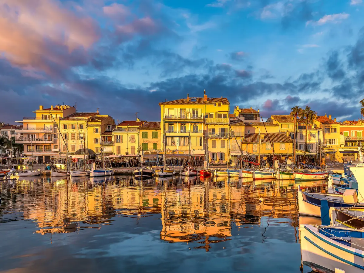 O porto de Sanary-sur-Mer ao pôr do sol, os seus barcos de pesca tradicionais e as suas fachadas amarelas