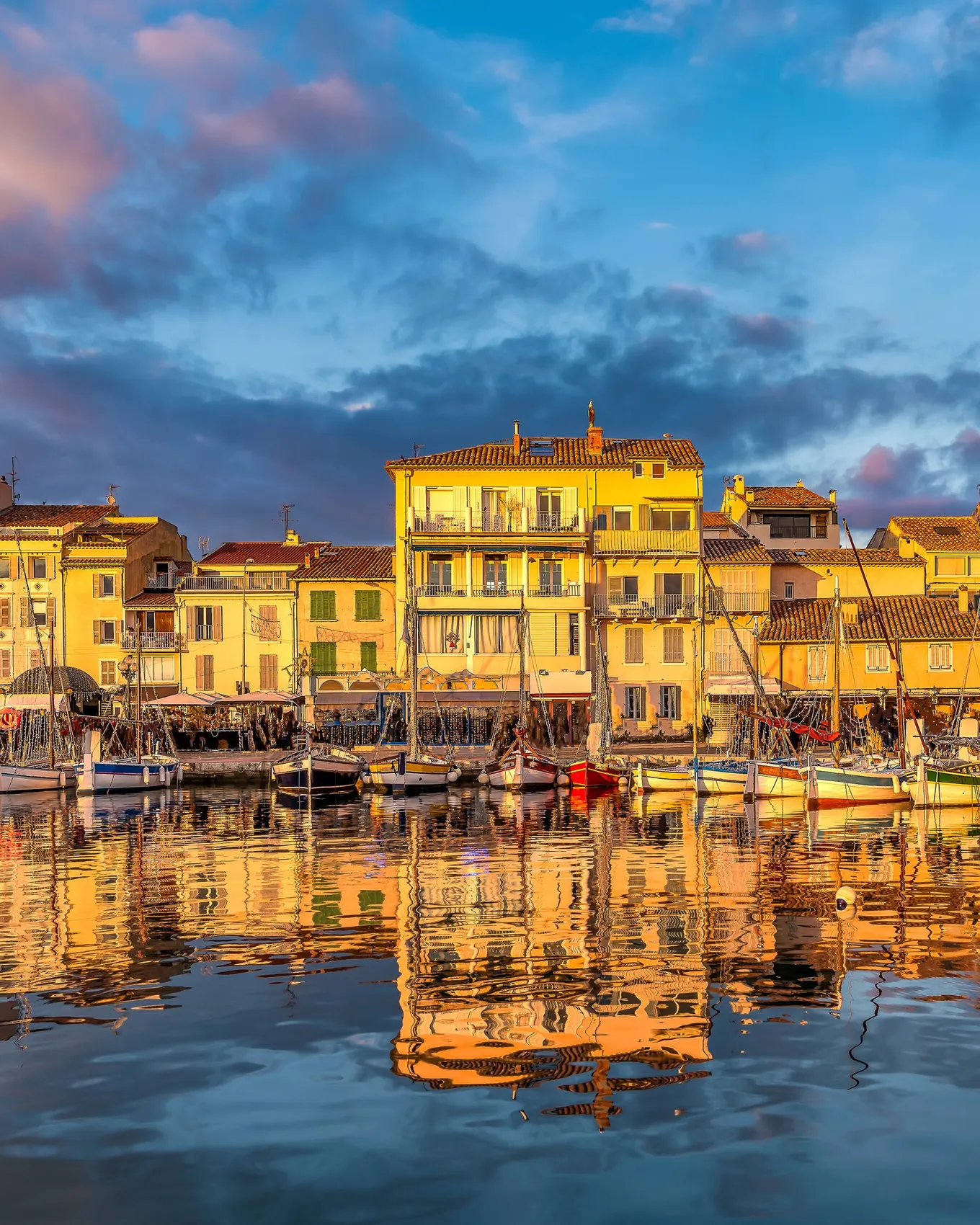 The port of Sanary-sur-Mer at sunset, its traditional fishing boats and its yellow façades
