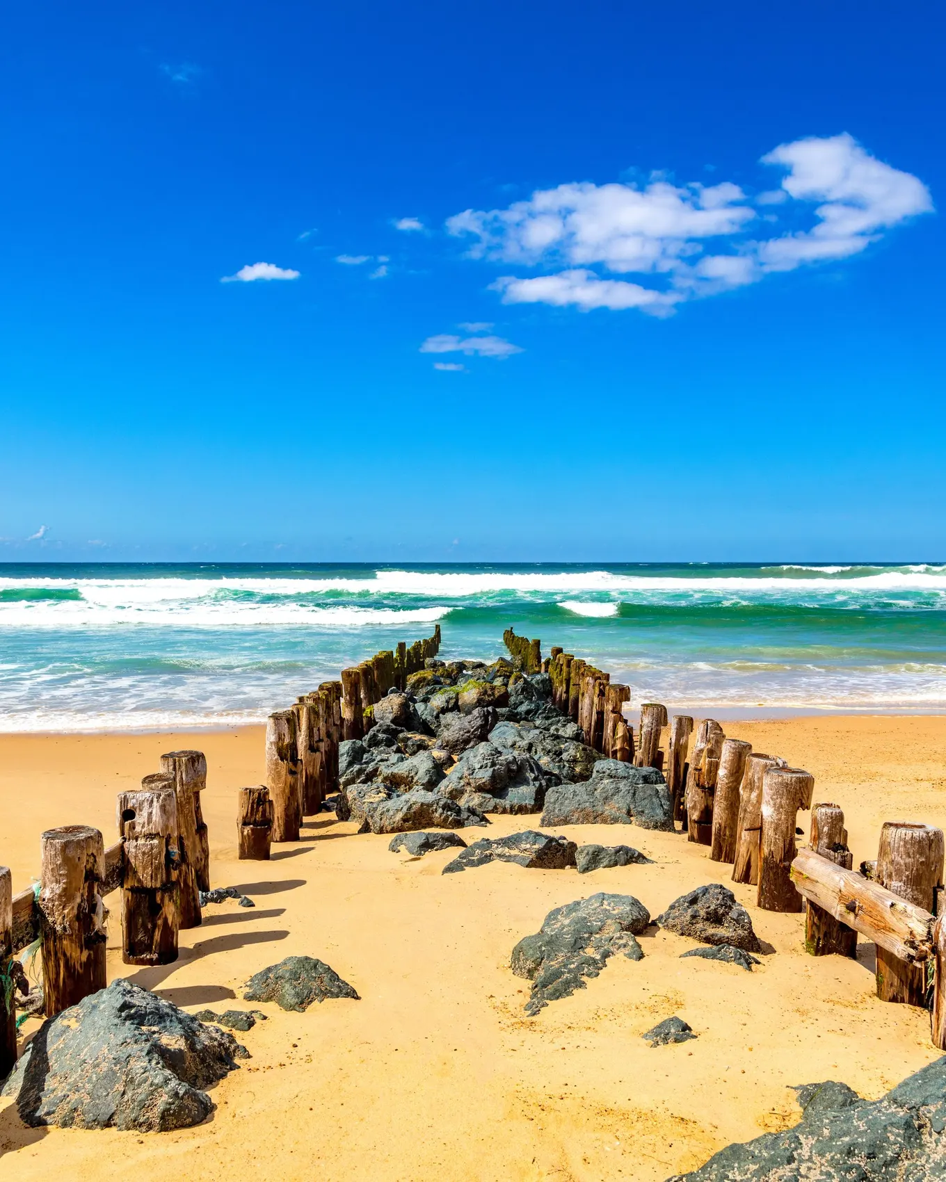 A groyne of wooden posts and rocks on Seignosse beach, facing the ocean