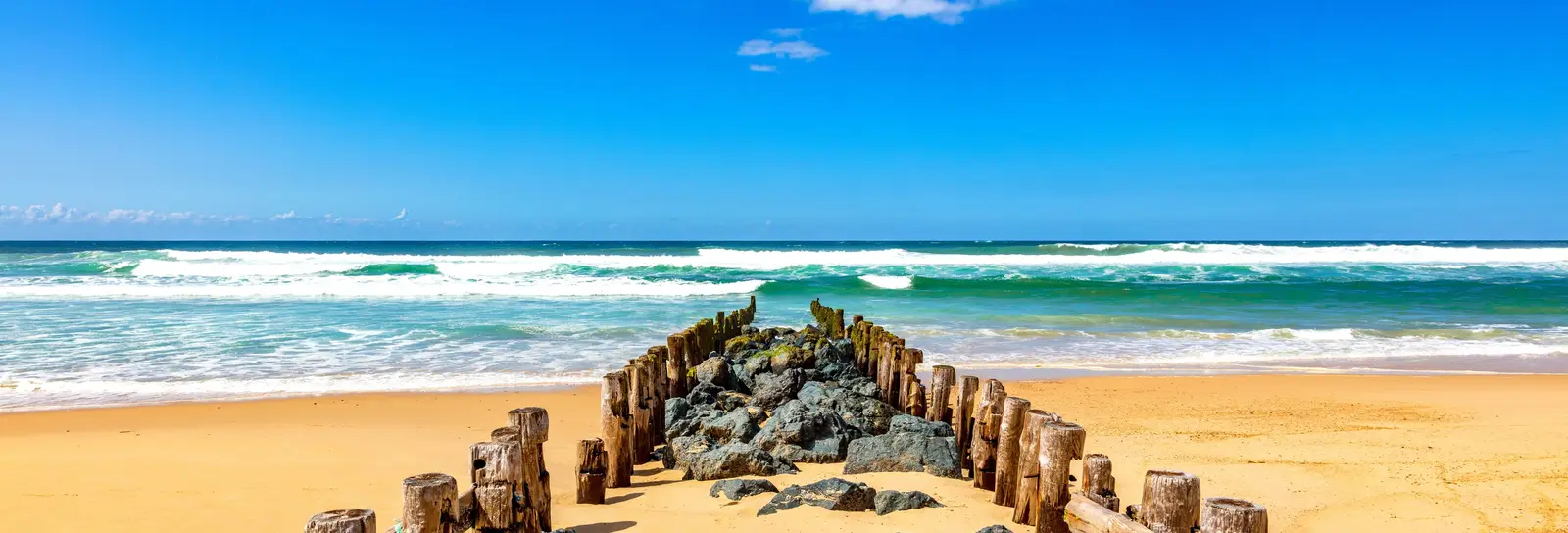 A groyne of wooden posts and rocks on Seignosse beach, facing the ocean