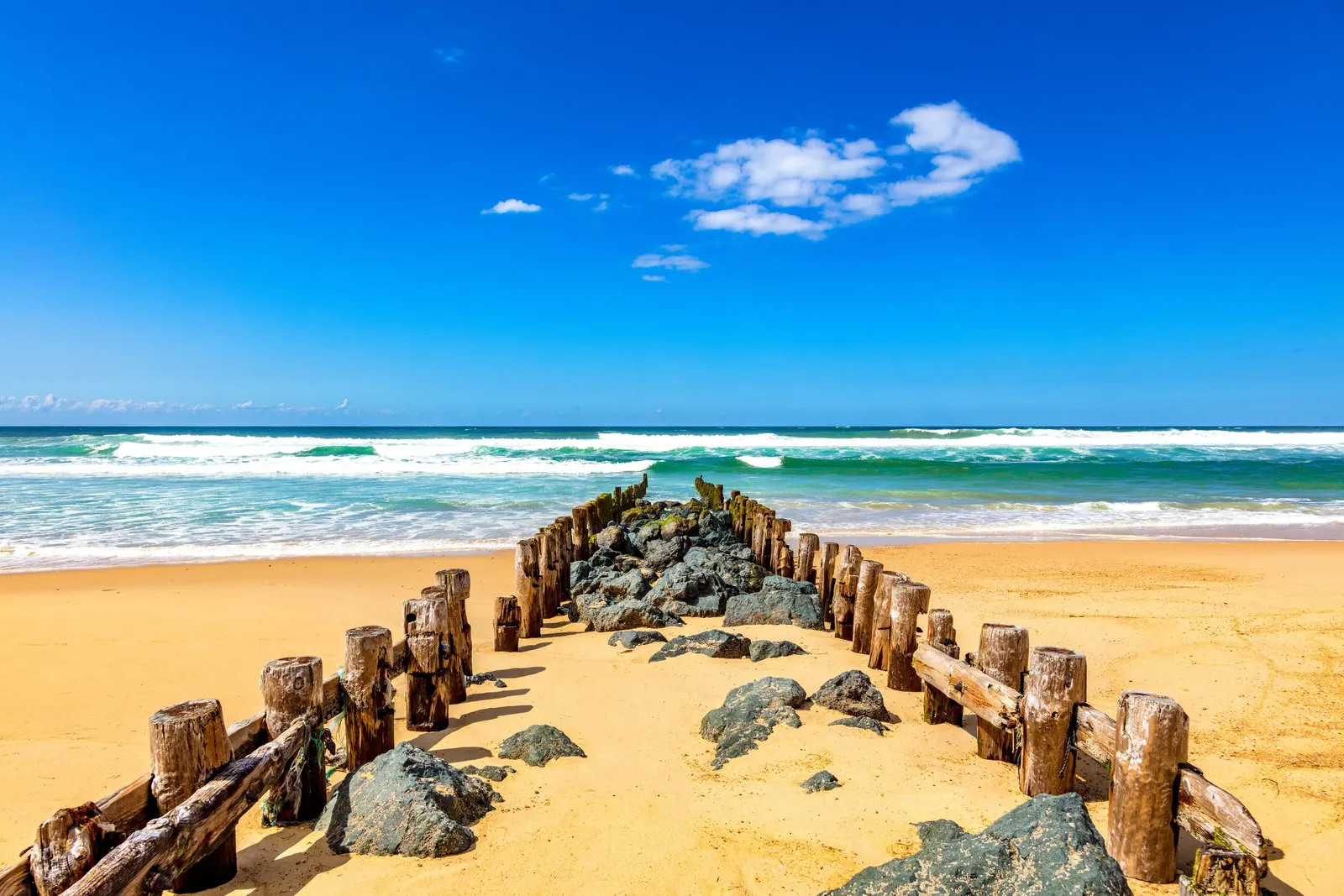 A groyne of wooden posts and rocks on Seignosse beach, facing the ocean