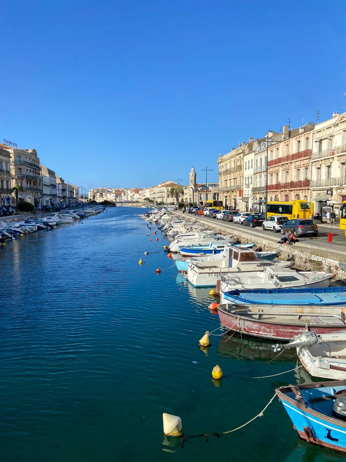 The Sète canal in portrait, the small boats and the quayside buildings
