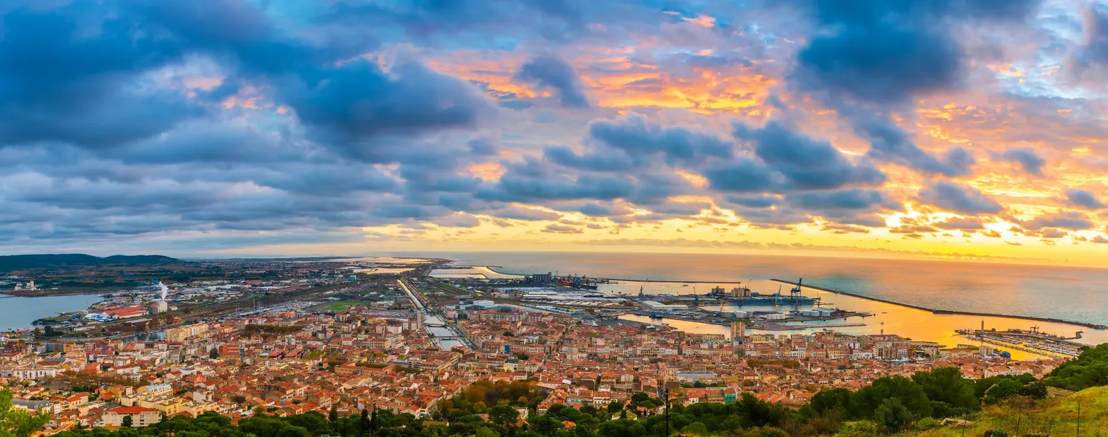 Sète au lever du soleil depuis le mont Saint-Clair, la ville, le port et la mer sous un ciel orangé