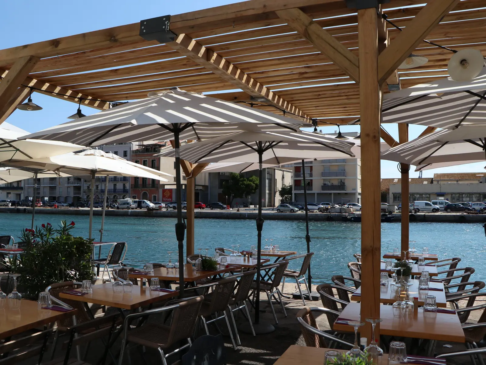 Une terrasse de restaurant sous les parasols, au bord du canal