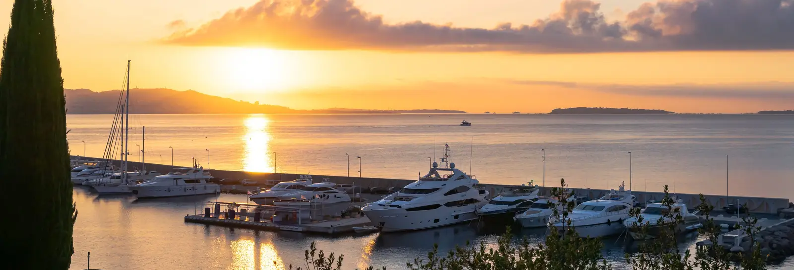 Le port de Théoule-sur-Mer au lever du soleil, ses yachts à quai et le golfe à l’horizon