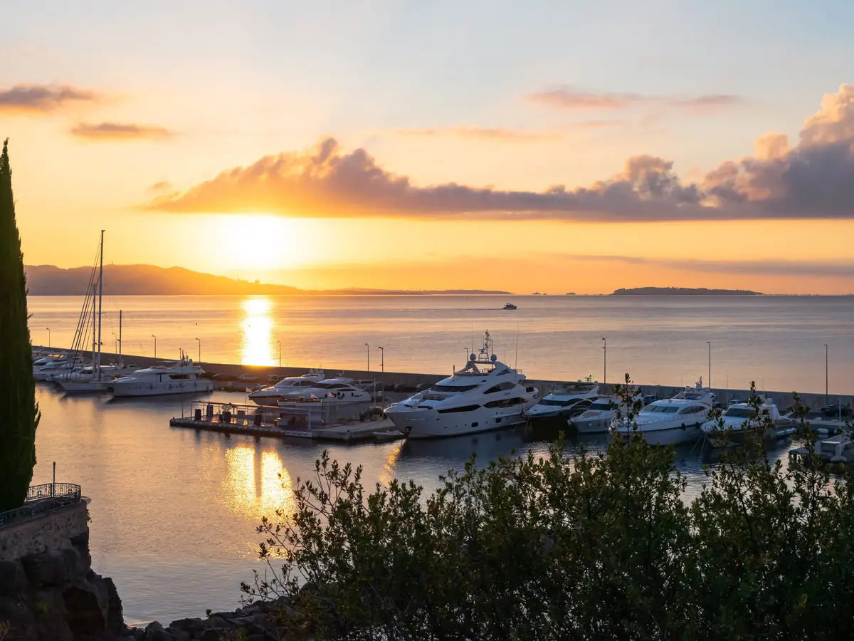 The harbour of Théoule-sur-Mer at sunrise, yachts at the quay and the gulf on the horizon