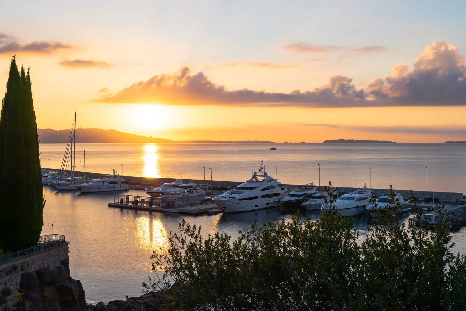 The harbour of Théoule-sur-Mer at sunrise, yachts at the quay and the gulf on the horizon
