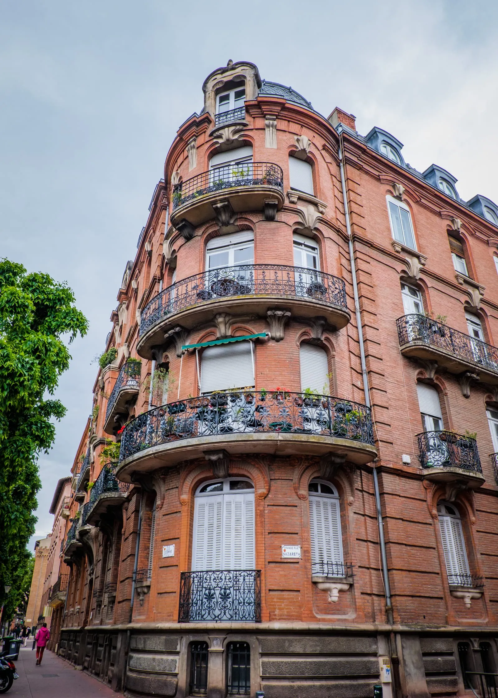 Un immeuble de brique aux balcons arrondis en fer forgé