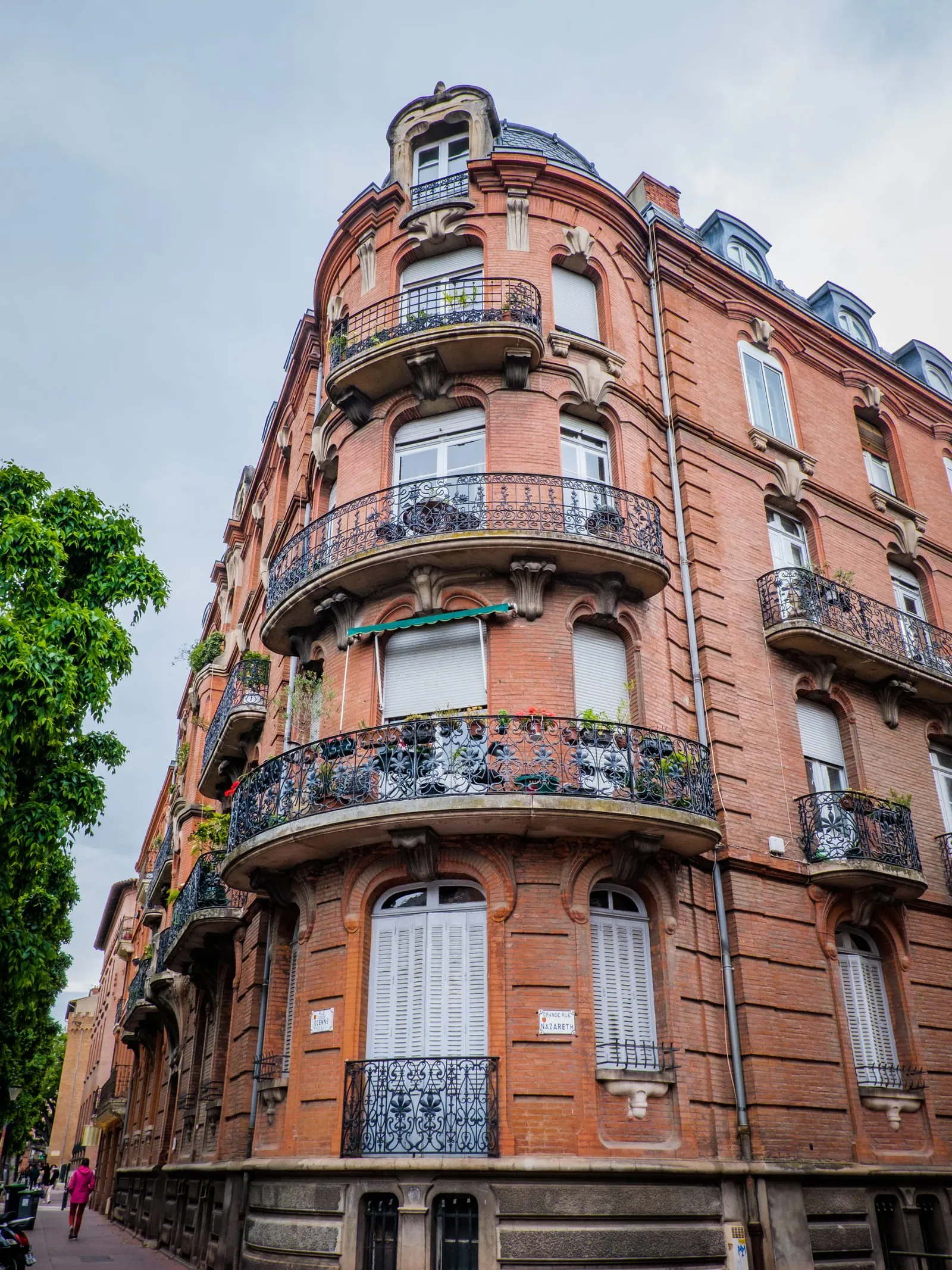 A brick building with rounded wrought-iron balconies
