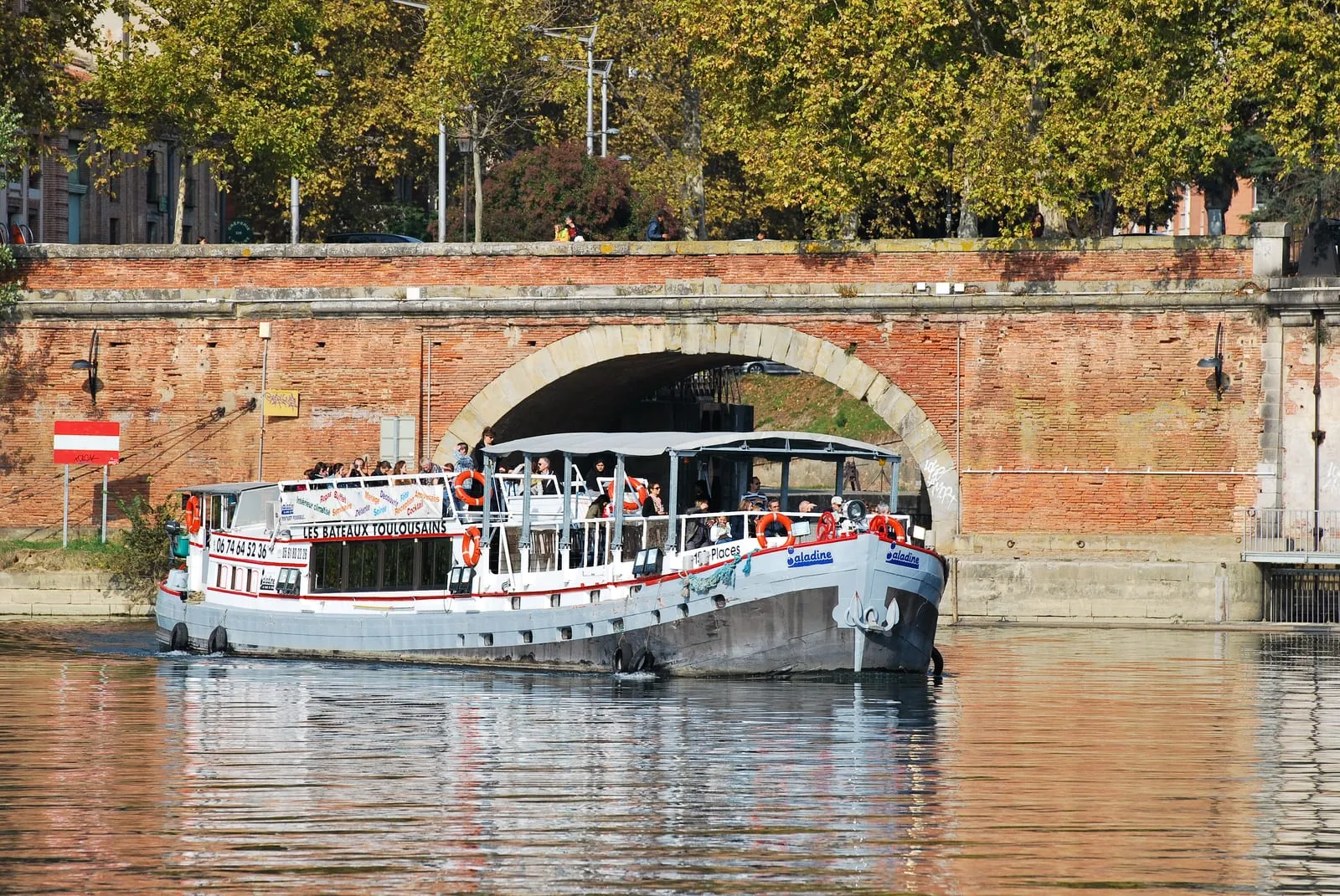A pleasure boat passing under a brick bridge
