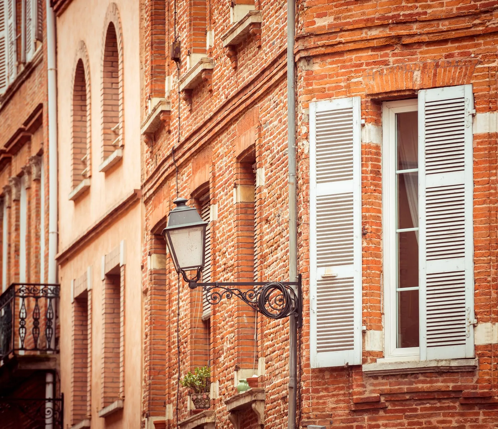 A brick façade with white shutters and its lantern