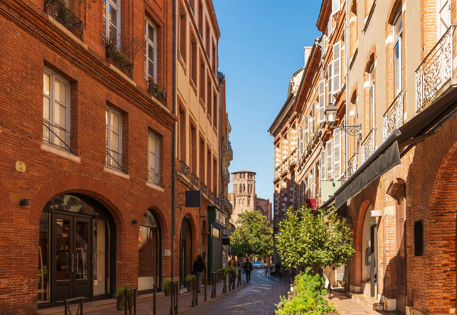 Une rue de briques roses de Toulouse et son clocher au fond
