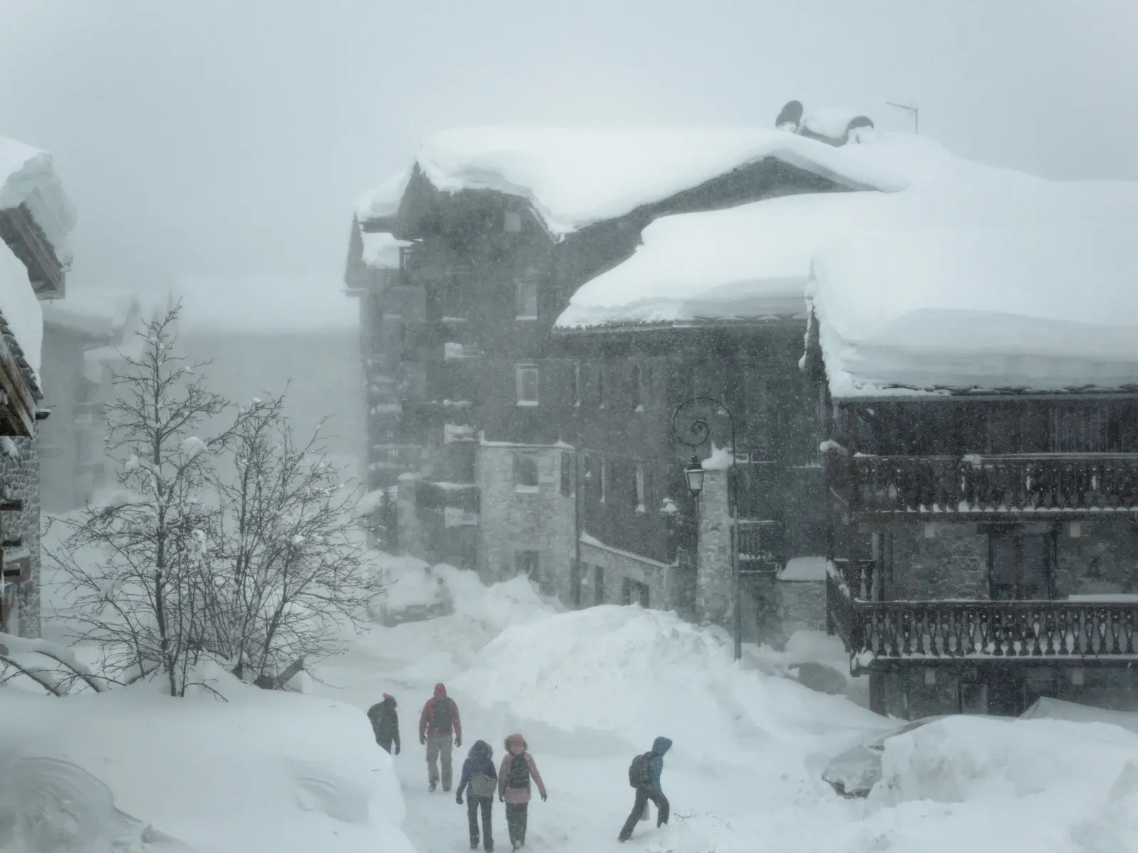 Os chalés de pedra e madeira de Val-d’Isère sob uma tempestade de neve, transeuntes na rua