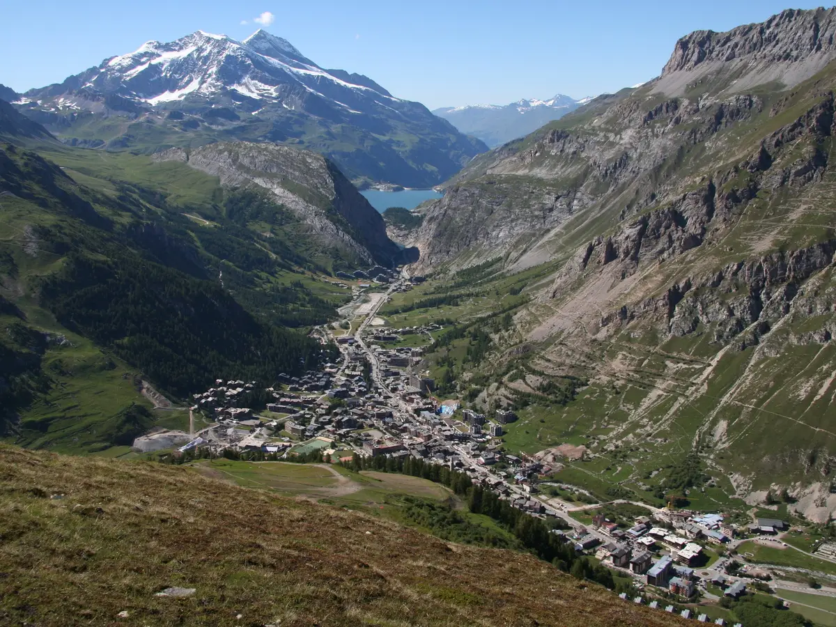 Val-d’Isère seen from the heights in summer, the village centre at the bottom of the Isère valley and the snowy peaks in the distance