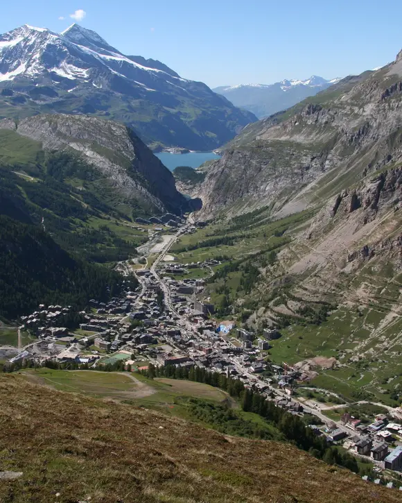 Val-d’Isère seen from the heights in summer, the village centre at the bottom of the Isère valley and the snowy peaks in the distance