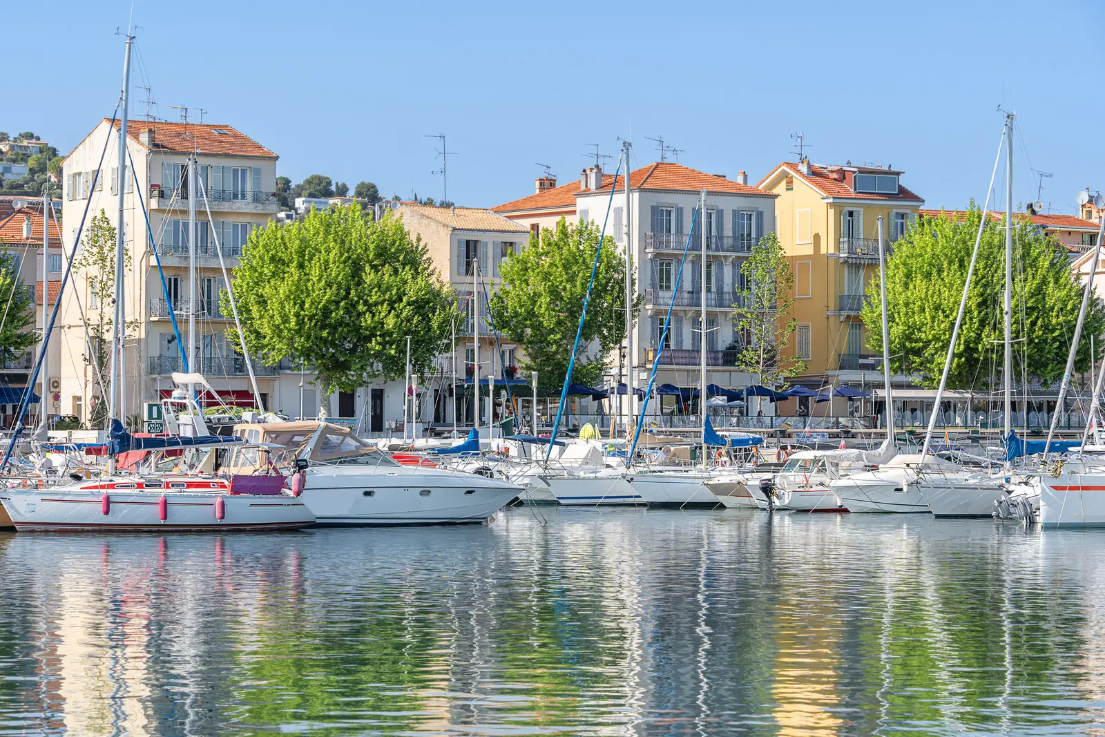 O Vieux-Port de Golfe-Juan, em Vallauris: os veleiros atracados sob os plátanos e as fachadas coloridas do porto