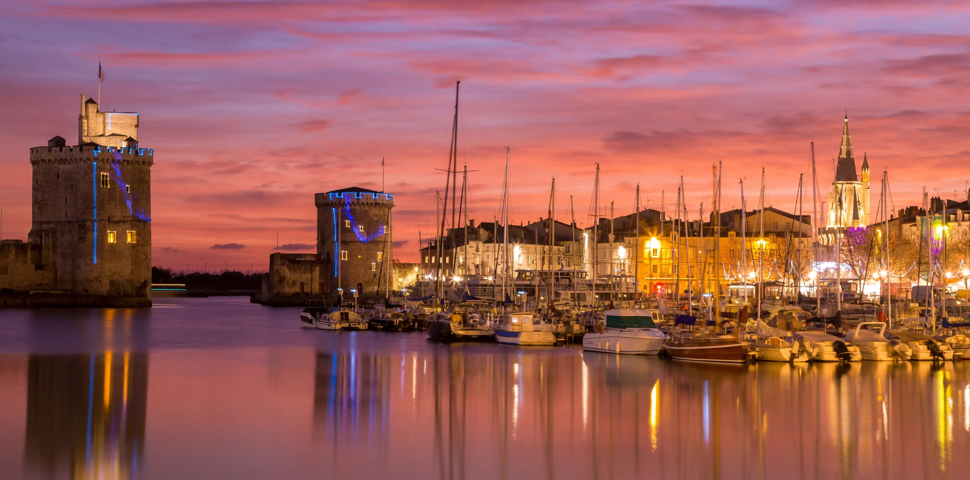 Les tours du Vieux-Port de La Rochelle au crépuscule et les mâts des voiliers amarrés