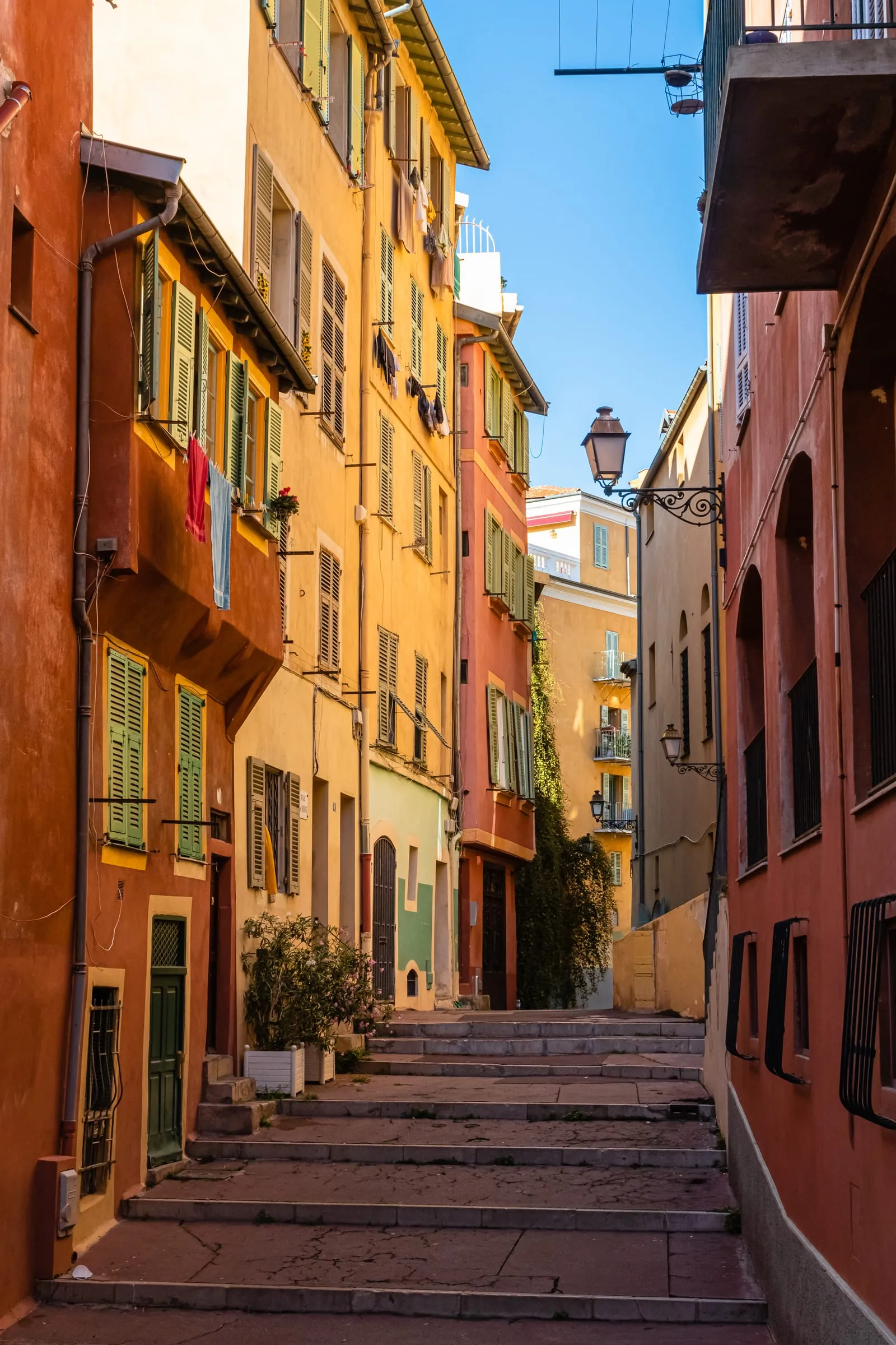 Une ruelle aux façades ocre et rouge passant sous un arceau, à Nice