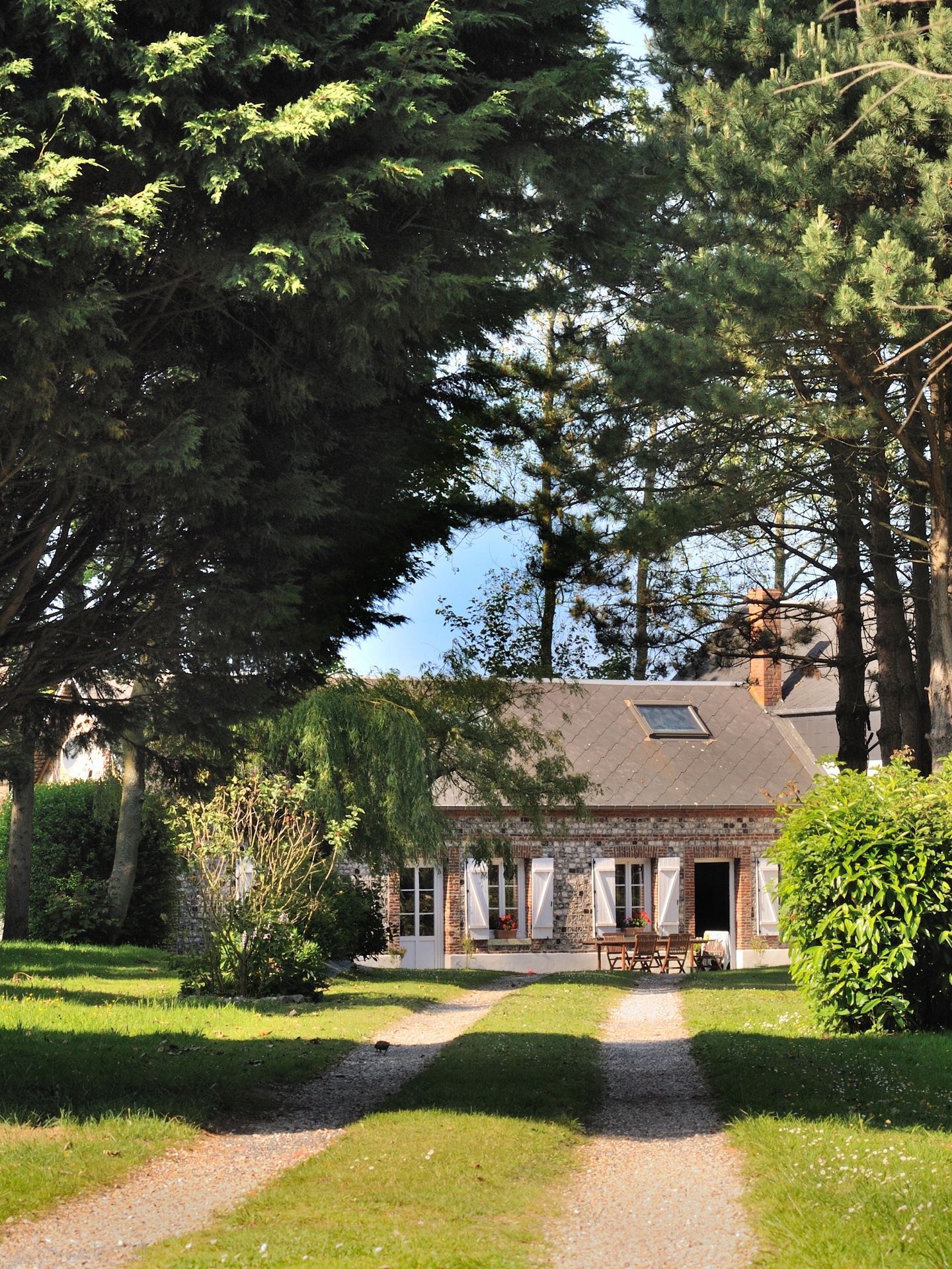 Maison de campagne en pierre au bout de son allée de gravier, en Normandie