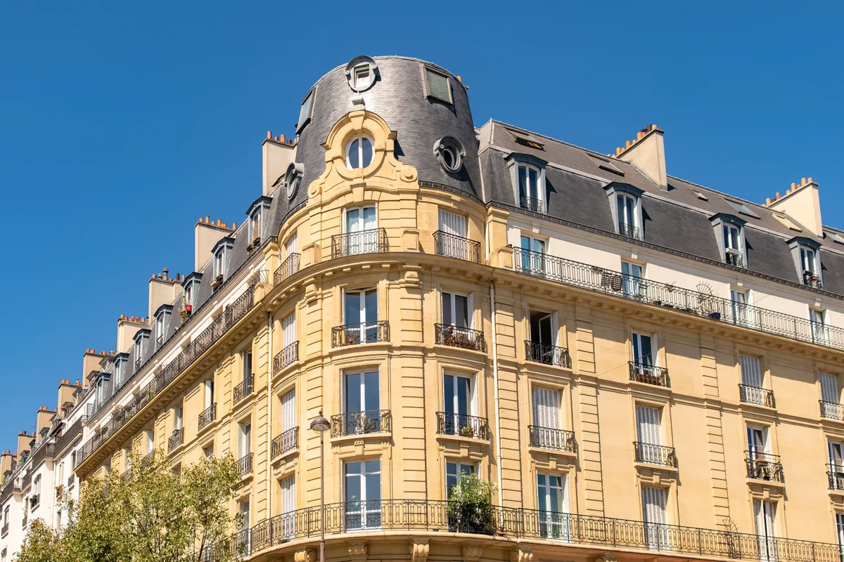 Immeuble haussmannien d’angle à Paris, pierre de taille, balcons en fer forgé et toit en zinc